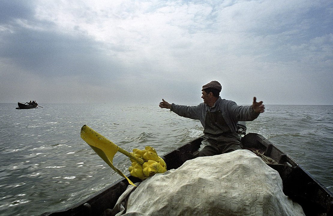 A playful fishermen returning home after working shows to the others the size of fish he got today, Sfantu Gheorghe
