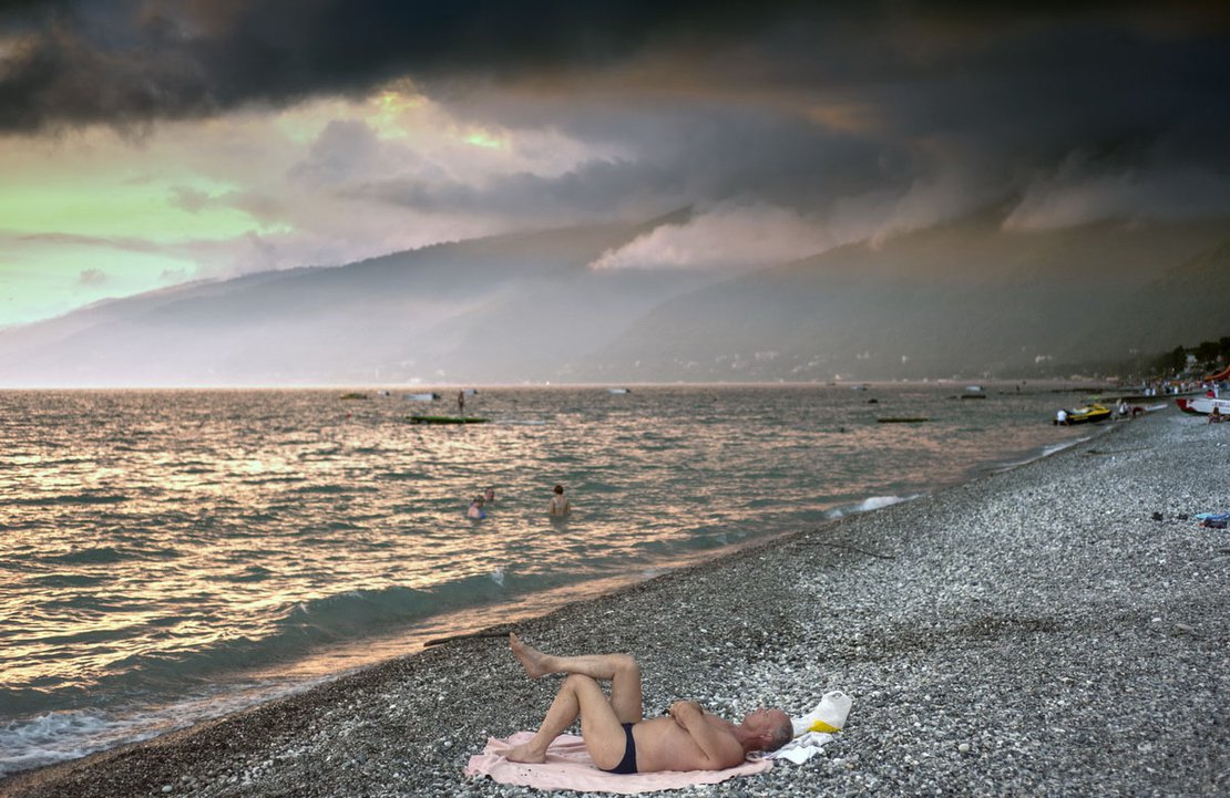 A man in swimming trunks lies on the beach in Gagra, the busiest resort in Abkhazia, very close to Sochi Olympic site and Russian border.