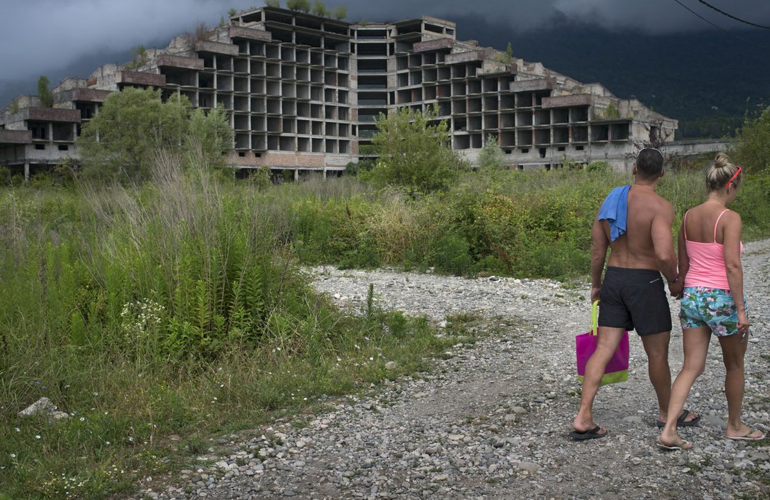Tourist walk by an abandoned hotel in Gagra, the busiest resort in Abkhazia, very close to Sochi Olympic site and Russian border.
