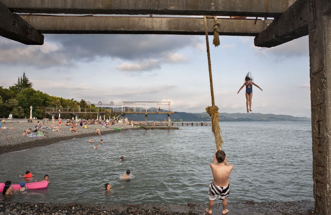 A girl jumps into the sea from the remnants of a concrete structure built by the shore, Sukhumi beach